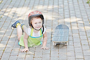 Little girl in protective helmet lies on park path