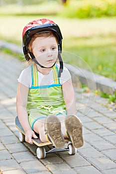 Little girl in protective helmet rides down park