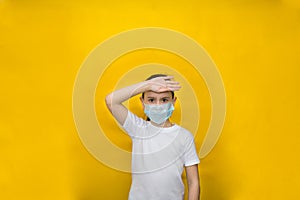 Little girl in a protective mask measures the temperature her hand on a yellow background Protection against coronavirus