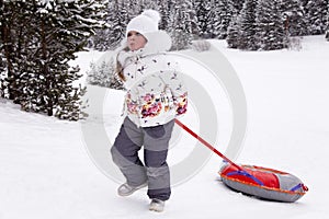 Little girl pulling the strap snow tubing.