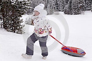 Little girl pulling the strap snow tubing.