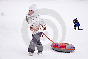 Little girl pulling the strap snow tubing.