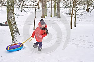 Little girl pulls down a hill sled. child in winter tubing