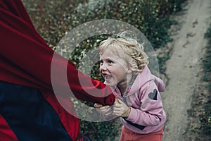 A little girl pulls her brother& x27;s sleeve while walking in nature. A happy child plays with his family in the fresh