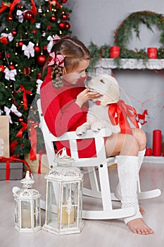 A little girl with a puppy Golden Retriever on a background of Christmas tree