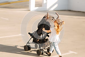 A little girl is pushing her baby carriage