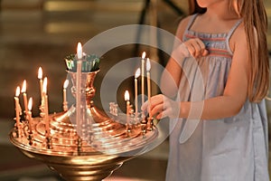 A little girl puts a candle in church. Orthodoxy