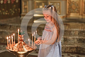 A little girl puts a candle in church. Orthodoxy photo