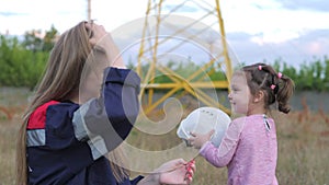 A little girl puts on a helmet for her mother to an engineering worker. Concern for future generations and the