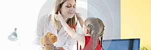 Little girl putting stethoscope on to doctor pediatrician in clinic