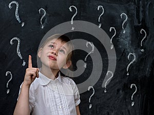 Little girl with question marks on blackboard. Concept for confusion, brainstorming and choice.