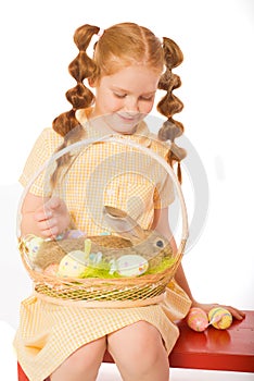 Little girl with a rabbit in basket easter eggs