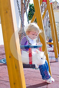 Little girl and rabbit on swings