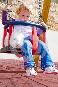 Little girl and rabbit on the swings