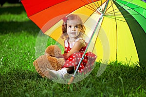 Little girl with a rainbow umbrella in park