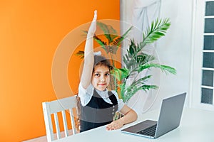 Little girl raising her hand up for answer at lesson at school