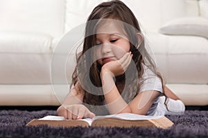 Little Girl Reading Bible on Carpet