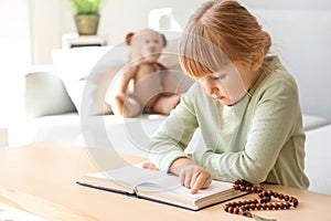 Little girl reading Bible at home