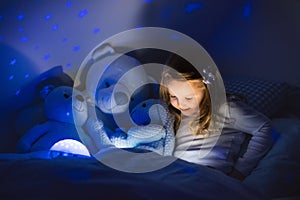 Little girl reading a book in bed