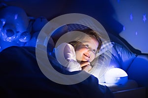 Little girl reading a book in bed