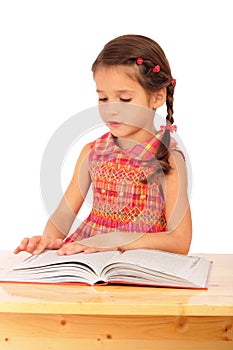 Little girl reading book on the desk