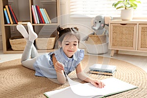 Little girl reading book on floor