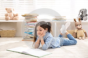 Little girl reading book on floor