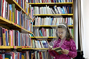 Little girl reading a book in the library