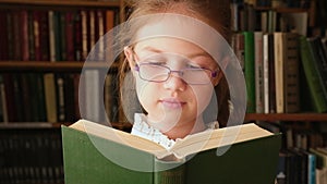 Little girl reading book in library close up. Child in bookstore