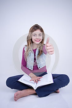 Little Girl reading a book and making a positive sign