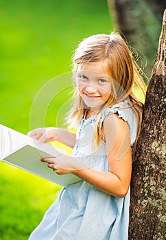 Little girl reading book outside