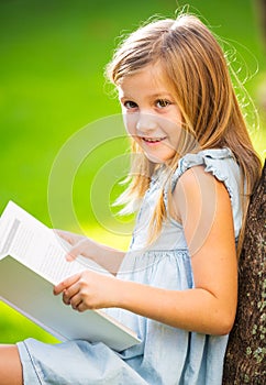 Little girl reading book outside