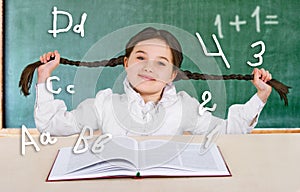 Little girl reading a book smiling teenager near a school board