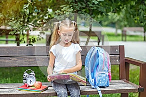 Little girl is reading books in the school park. The concept of school, study, education, friendship, childhood