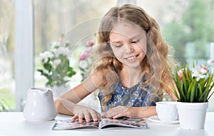 Little girl reading magazine