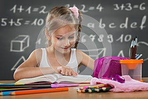 Little girl reading in school, written job behind the plate