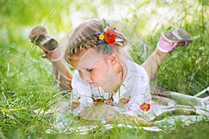 Little girl reading tales lying in green grass