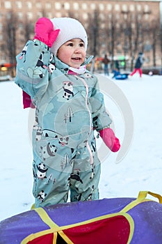 Little girl is ready for riding on snow tubing from slope in city park