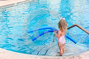 Little girl ready to jump into the pool with noodle