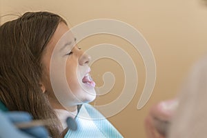 Little girl at the reception in the dentist& x27;s office. little girl sitting in a chair near a dentist after dental treatment.