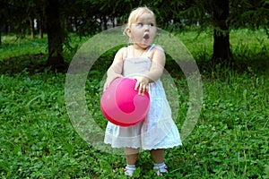 Little girl with red balloon in the forest.