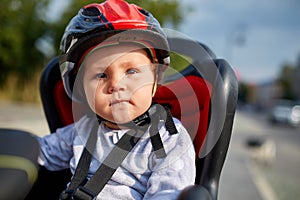 Little girl in red and black helmet seat bicycle in city park