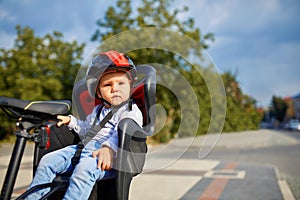 Little girl in red and black helmet seat bicycle in city park