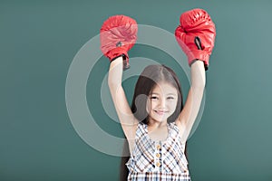 little girl with red boxing gloves stand before chalkboard