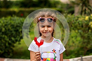 Little girl with red caramel lollipop cockerel