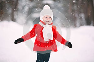 Little girl in red coat with a teddy bear having fun on winter day. girl playing in the snow