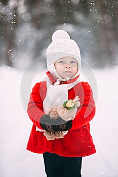 Little girl in red coat with a teddy bear having fun on winter day. girl playing in the snow