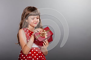 Little girl in red dress holding her present