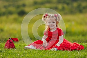 little girl in a red dress sitting on the lawn