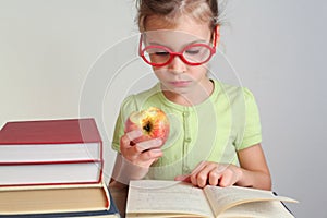 Little girl in red glasses read book